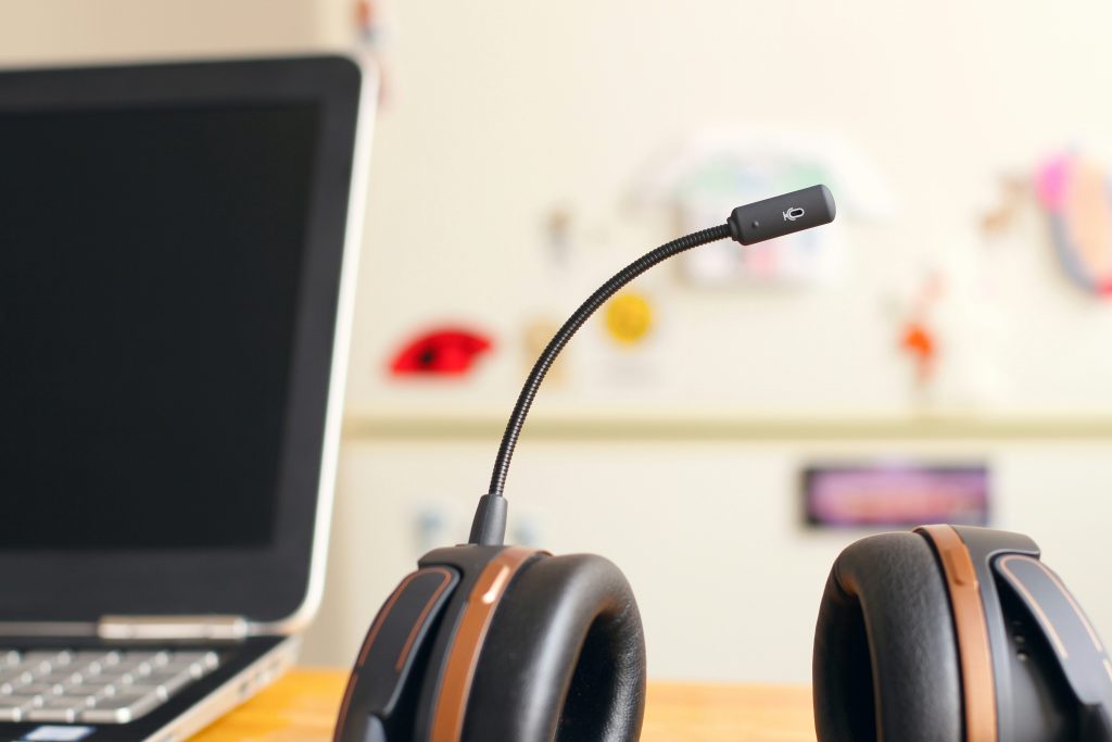 headphones with microphone beside a laptop